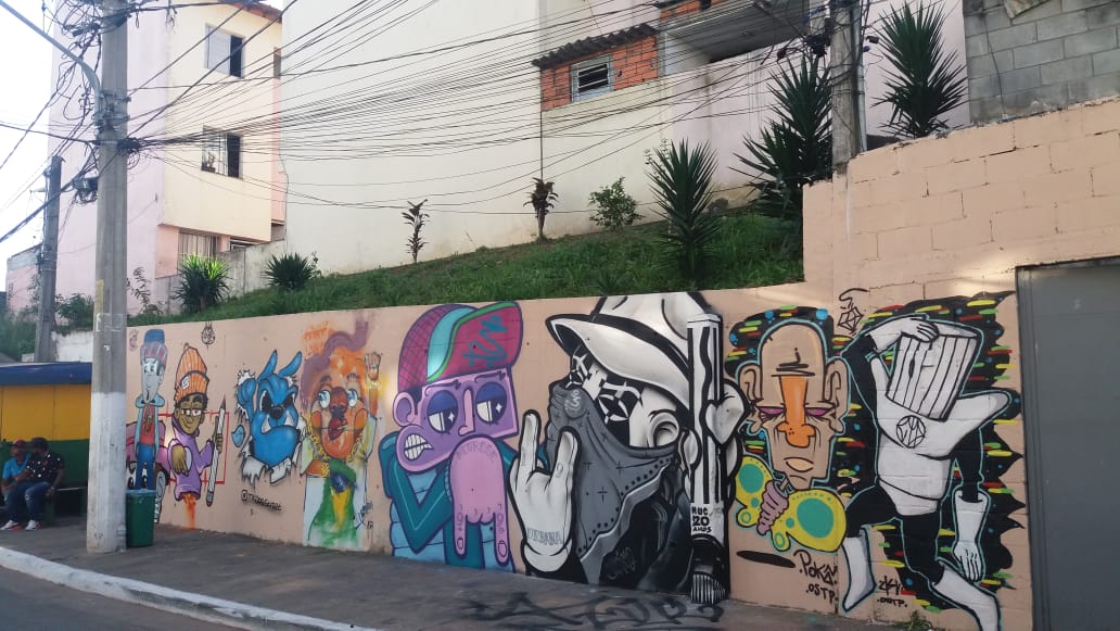 Muro grafitado com desenhos de animais e pessoas 